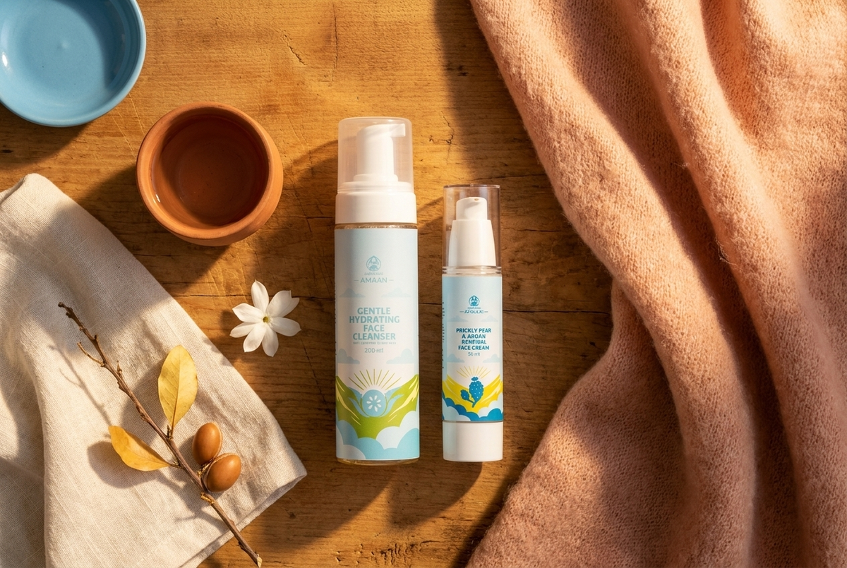Face Duo morning ritual flatlay · AMAAN + AFOULKI side by side on honey wood, jasmine, dried argan branch