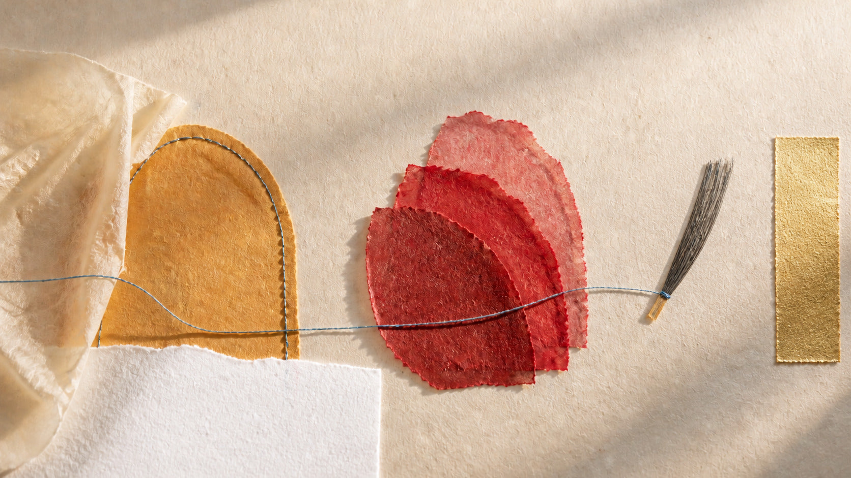 Hand-layered cream, ochre and red paper connected by blue thread, with black fibres and a gold paper detail